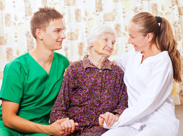 Mulher idosa com os jovens médicos — Fotografia de Stock