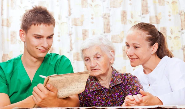 Elderly woman with the young doctors — Stock Photo, Image