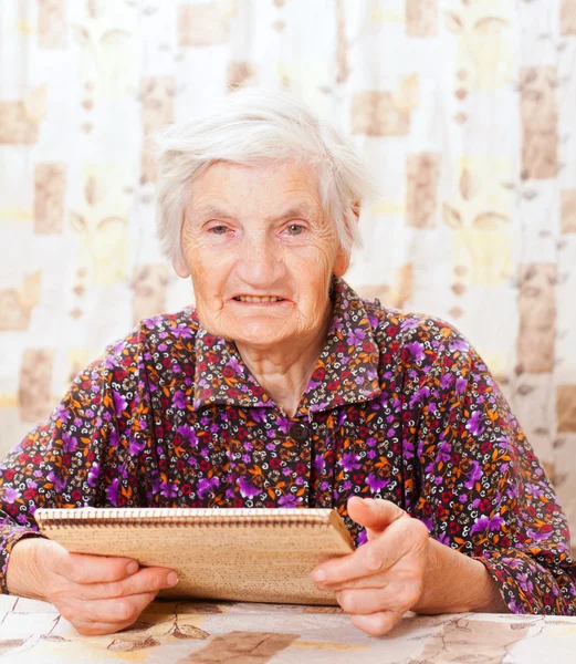 Elderly happy woman read something from the book — Stock Photo, Image