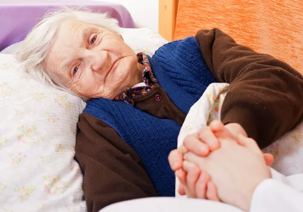 Anciana mujer solitaria descansa en la cama — Foto de Stock