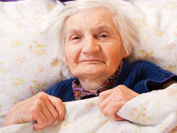 Elderly lonely woman rests in the bed — Stock Photo, Image