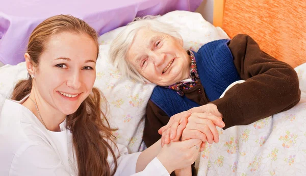 Jovem médico segura as mãos da mulher idosa — Fotografia de Stock