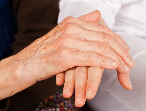 Joven médico sostiene las manos de la anciana — Foto de Stock