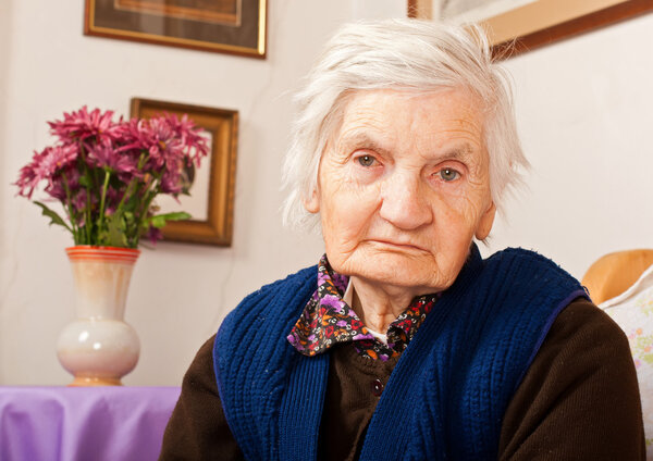 Elderly lonely woman sits on the bed