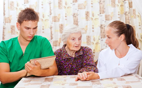 Elderly woman with the young doctors — Stock Photo, Image