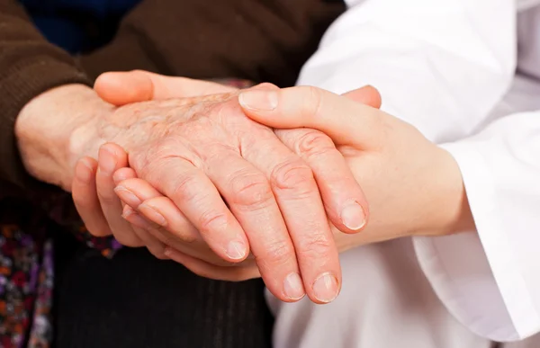 Genç doktor, yaşlı kadının ellerini tutar — Stok fotoğraf