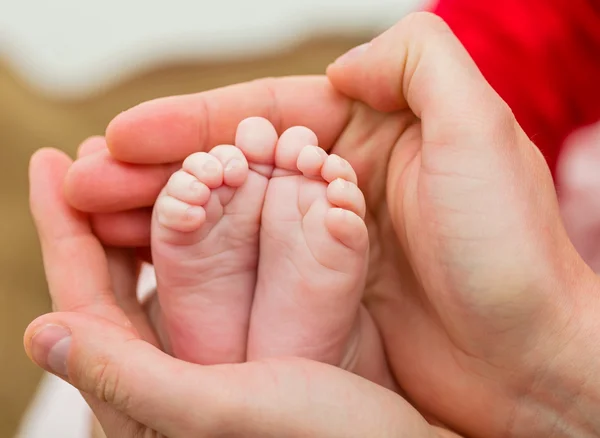 Pieds de bébé dans les mains du père — Photo