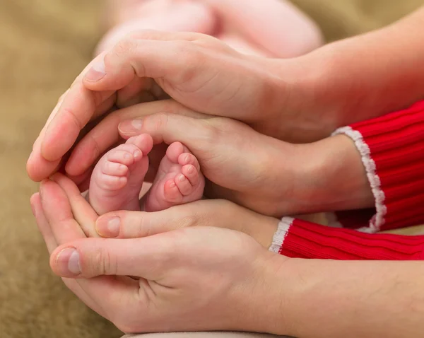 Pieds de bébé entre les mains des parents — Photo