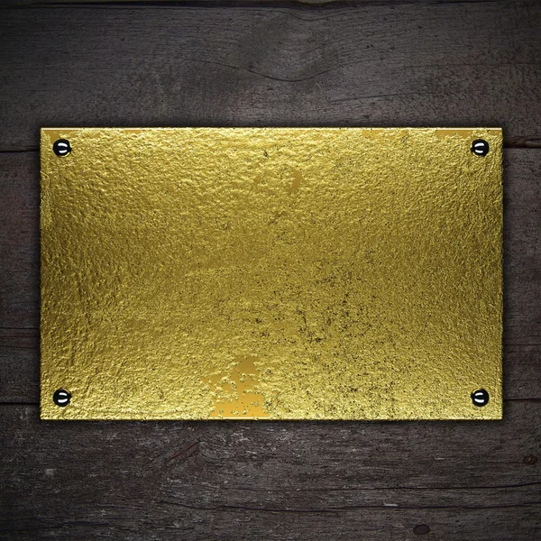 Placa de metal dourado no fundo de madeira. Modelo para design — Fotografia de Stock