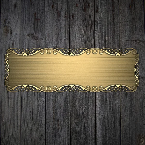 Hermoso patrón en una placa de oro sobre un fondo de madera —  Fotos de Stock