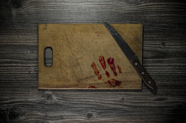 Grunge wooden background with a bloody hand print on the cutting board — Stock Photo, Image