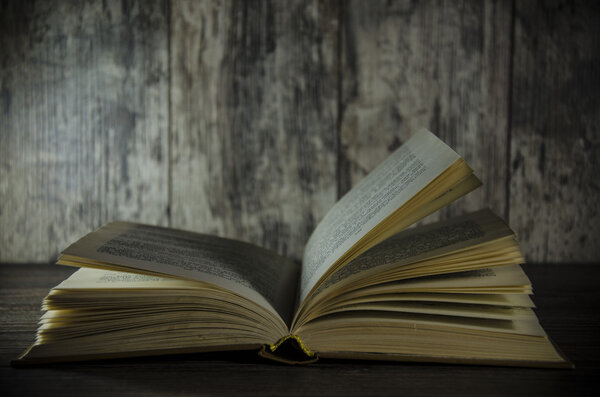 Vintage book, open, on old wooden table, with clipping path