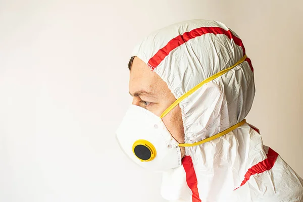 portrait of a man in a respirator and protective suit stands on a white background