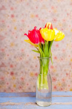 Ahşap masadaki cam vazoda laleler