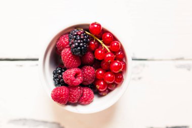 Beyaz arka planda bir kasede taze meyveler.