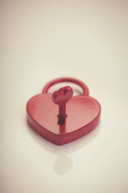 Beyaz arkaplanda anahtarı olan kırmızı kalp kilidi