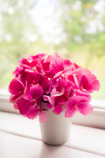 beautiful pink flowers in vase on windowsill