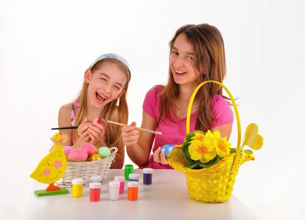 Páscoa - Duas meninas, cesta com ovos coloridos, tinta para colorir e um vaso de flores — Fotografia de Stock