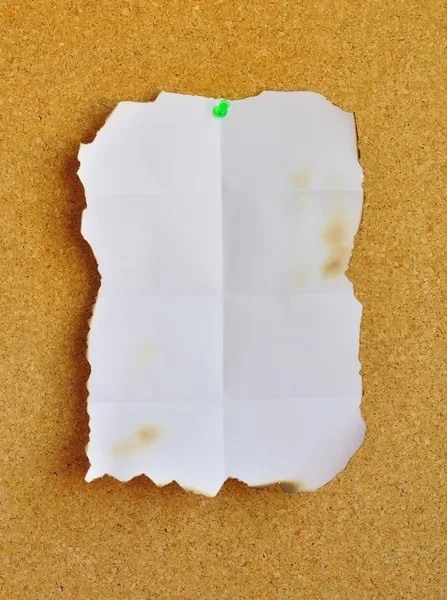 Burned white sheet pinned on cork bulletin board
