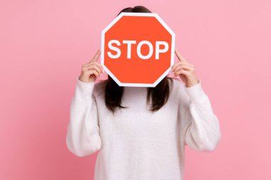 Siyah saçlı, yüzünü kırmızı dur işaretinin arkasına saklayan, içki yasağı olan beyaz kazak giyen kimliği belirsiz bir kadının portresi. Pembe arka planda kapalı stüdyo çekimleri.