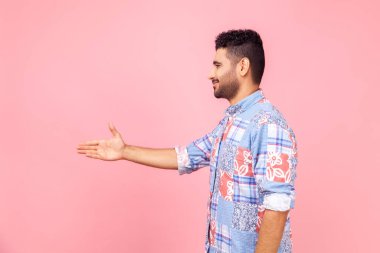 Dost canlısı, mavi tişörtlü, samimi sakallı bir adamın el sıkışması, iş görüşmesinde tanışması, yeni insanlarla tanışması. Pembe arka planda kapalı stüdyo çekimleri.