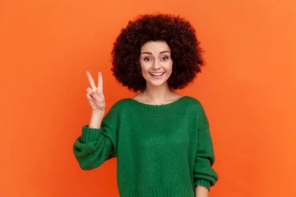스타일의 여자가 친환경 스웨터를 어여쁜 미소를 카메라를 바라보며 평화의 몸짓을 — 스톡 사진