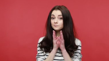 Parmaklarıyla jestler yapan, sinsi hileler ve hilekârlıklar yapan intikam planı üzerinde düşünen uzun kollu bir gömlek giyen bir kadın. Kırmızı arkaplanda kapalı stüdyo çekimleri.