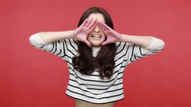 Kızgın esmer kadın kollarını açık tutuyor, yüksek sesle bağırıyor, haberlere dikkat çekiyor, gündelik tarzda uzun kollu gömlek giyiyor. Kırmızı arkaplanda kapalı stüdyo çekimleri.