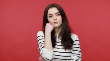 Kadının portresi, yüz yüze duran, üzgün düşünen, depresif ve ilgisiz görünen, gündelik tarzda uzun kollu gömlek giyen. Kırmızı arkaplanda kapalı stüdyo çekimleri.
