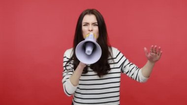 Elinde hoparlörle bağıran kadın portresi, katı kız bağırması, cinsiyet eşitliği sorunu, günlük tarz uzun kollu gömlek giymesi. Kırmızı arkaplanda kapalı stüdyo çekimleri.