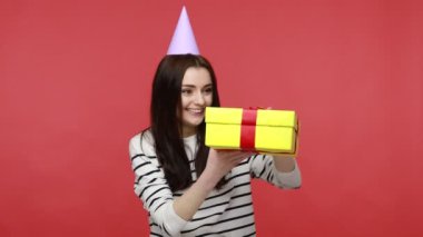 Parti konisi açılış hediye kutusundaki kadın portresi. Üzüntüsünü ifade ediyor. Hoş olmayan sürprizler alıyor. Kırmızı arkaplanda kapalı stüdyo çekimleri.