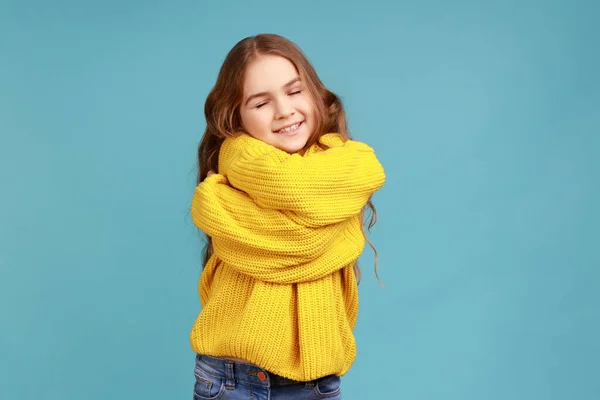 魅力的な少女の肖像画を自分自身を受け入れ 肯定的な自尊心から笑みを浮かべて 黄色のカジュアルなスタイルのセーターを着て 青い背景に隔離された屋内スタジオショット — ストック写真