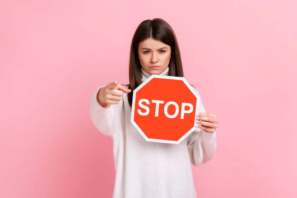 여자가 카메라 가리키며 스타일 스웨터 금지의 상징으로 표지판을 스튜디오 배경에서 — 스톡 사진