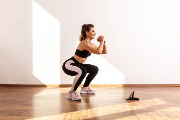 Vista Lateral Menina Magro Desportivo Agachamento Casa Assistindo Treinamento Vídeo — Fotografia de Stock