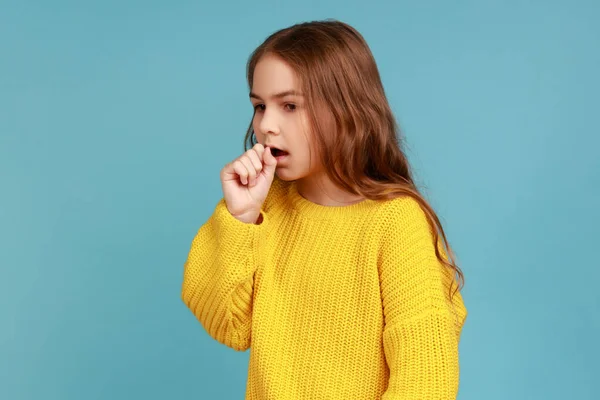 有流感症状 手靠嘴 穿着黄色休闲装的不健康小女孩的肖像 室内拍摄被蓝色背景隔离 — 图库照片