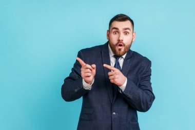 Vay canına, şu reklamlara bak! Resmi stil takım elbise giyen şaşırmış bir adamın portresi fikir sunumu için boş fotokopi alanı gösteriyor. Mavi arka planda kapalı stüdyo çekimi.