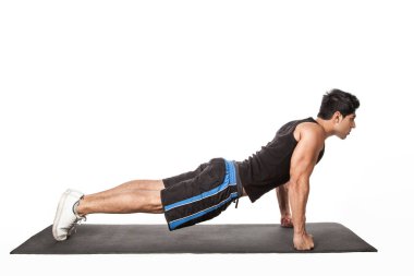 Kalas pozisyonunda duran güçlü yakışıklı atletik adamın portresi fitness paspası üzerinde çalışıyor, düz kollar üzerinde Phalakasana egzersizi yapıyor. Beyaz arka planda izole edilmiş kapalı stüdyo görüntüleri.