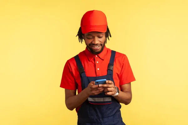 Uśmiechnięty Pracownik Noszący Jednolitą Wiadomość Czytania Telefonie Komórkowym Aplikacji Zamówienia — Zdjęcie stockowe