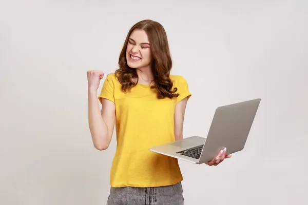 Portret Entuzjastycznej Szczęśliwej Nastolatki Żółtej Koszulce Zaciskającej Pięść Trzymającej Laptopa — Zdjęcie stockowe