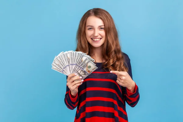 낙관적 여자가 가벼운 줄무늬의 스웨터를 손가락을 가리키며 지폐의 팬으로 스러운 — 스톡 사진