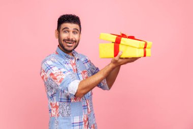 El ele tutuşan mutlu, heyecanlı, sakallı bir adam. Sarıya boyanmış hediye kutusunun yarısı açıldı. Kameraya heyecan ve şaşkınlıkla bakıyor. Pembe arka planda kapalı stüdyo çekimleri.