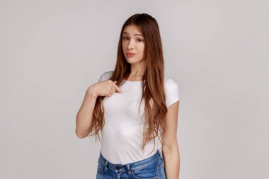 Ben buyum. Kendini gösteren kibirli bir kadının portresi. Bencil ve kibirli görünüyor. Kendi başarılarından gurur duyuyor, beyaz tişört giyiyor. Gri arka planda izole edilmiş kapalı stüdyo görüntüleri.