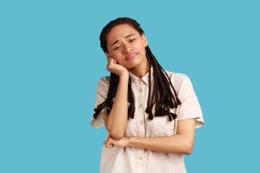 Siyah saçlı sıkkın kadın ellerini yanaklarından ayırmıyor, ilginç görünmeyen bilgiler veriyor, sıkıcı toplantıları sevmiyor, beyaz gömlek giyiyor. Mavi arka planda kapalı stüdyo çekimi.