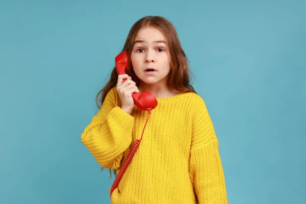 少女の肖像画 信じられないほどのニュースにショックを受け 黄色のカジュアルなスタイルのセーターを着て 会話に驚いて電話機を保持します 青い背景に隔離された屋内スタジオショット — ストック写真