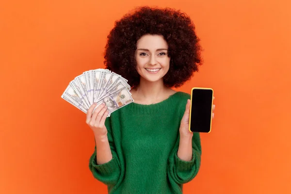 스타일의 여성이 지폐가 스마트폰을 스튜디오는 주황색 배경에서 — 스톡 사진