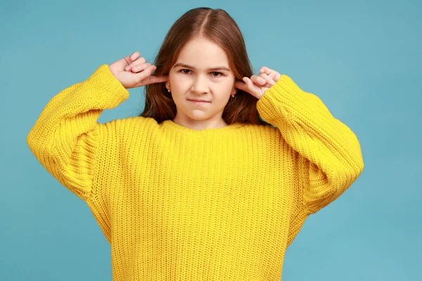 小さな女の子を閉じ耳で親のアドバイスを聞いていない立っての肖像画 養育を無視して 黄色のカジュアルなスタイルのセーターを着ている 青い背景に隔離された屋内スタジオショット — ストック写真