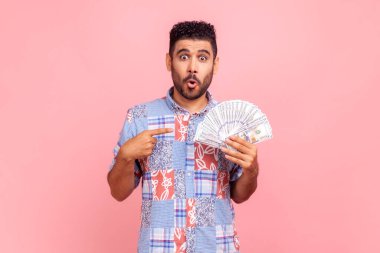 Şaşırmış sakallı adamın portresi dolar nakit, para değişimi, faiz oranıyla şok olmuş, kameraya şaşkınlıkla bakıyor. Pembe arka planda kapalı stüdyo çekimleri.