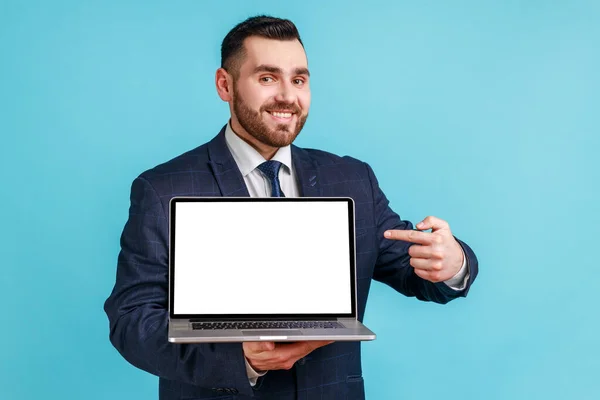 公式スタイルのスーツの肯定的な喜びのビジネスマンの肖像画は 空白の画面でノートパソコンを保持し カメラ インターネット広告で笑顔立っている 青い背景に隔離された屋内スタジオショット — ストック写真