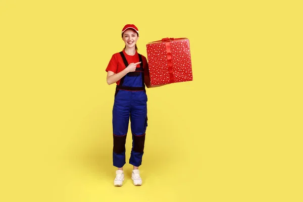 Full Length Portrait Courier Woman Standing Pointing Big Present Box — стоковое фото