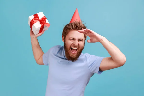 Portrait Excited Bearded Man Party Cone Holding Gift Box Looks – stockfoto